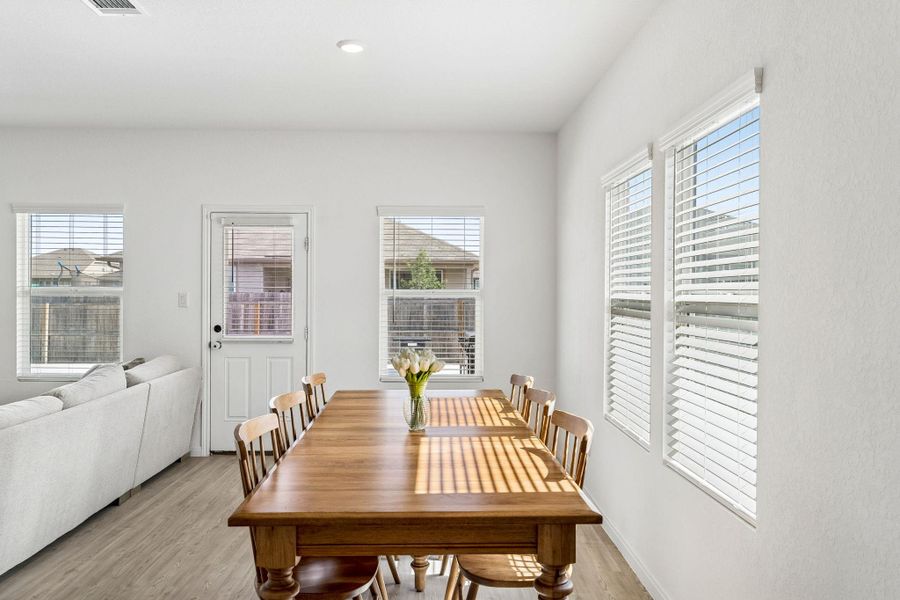 Natural light floods this dining area through multiple windows, enhancing the durable flooring.