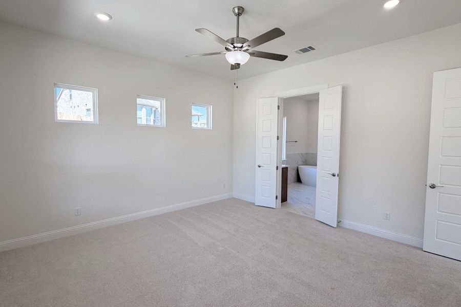 Unfurnished bedroom featuring light colored carpet, a ceiling fan, recessed lighting, and connected bathroom