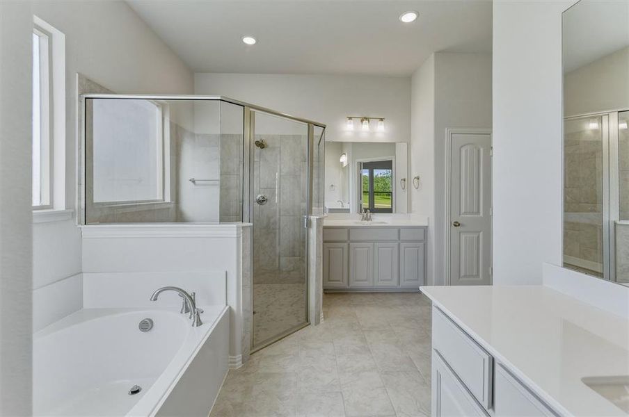 Spacious bathroom featuring a built-in bathtub with chrome fixtures, a glass-enclosed shower, dual vanity with light gray cabinetry and white countertops, and recessed lighting Spacious bathroom featuring a built-in bathtub with chrome fixtures, a glass-enclosed shower, dual vanity with light gray cabinetry and white countertops, and recessed lighting