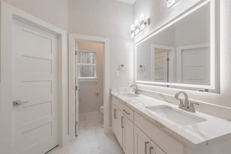 Bathroom featuring light marble finish flooring and double vanity