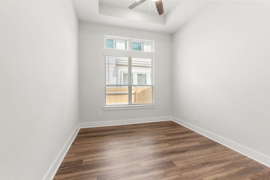 Unfurnished room featuring a ceiling fan, dark wood finished floors, baseboards, and a raised ceiling Unfurnished room featuring a ceiling fan, dark wood finished floors, baseboards, and a raised ceiling