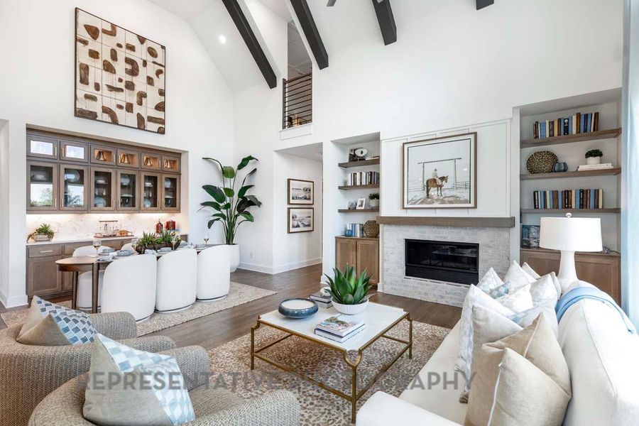 Living room featuring high vaulted ceiling, dark wood-style floors, a glass covered fireplace, beam ceiling, and ceiling fan Living room featuring high vaulted ceiling, dark wood-style floors, a glass covered fireplace, beam ceiling, and ceiling fan