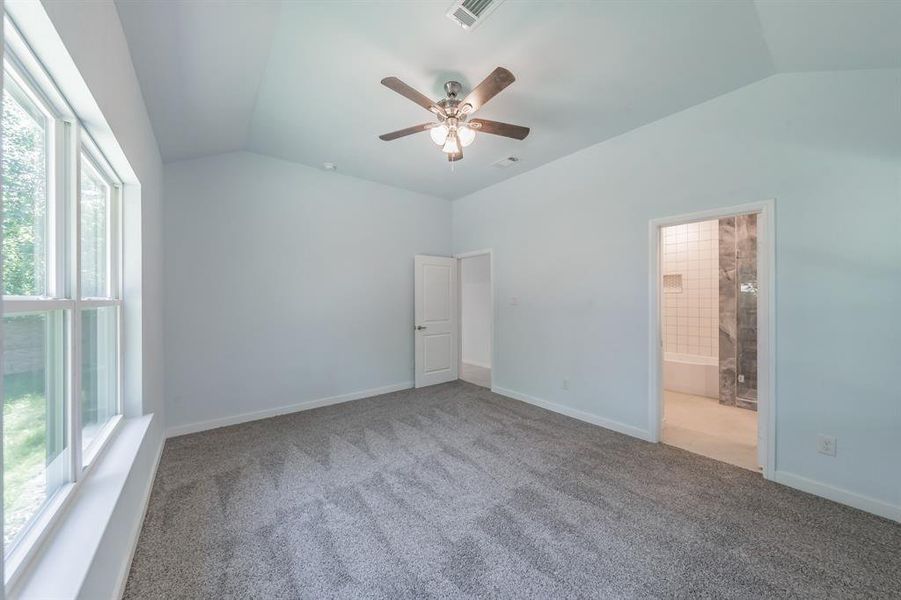 Unfurnished bedroom featuring vaulted ceiling, carpet floors, ensuite bathroom, and a ceiling fan Unfurnished bedroom featuring vaulted ceiling, carpet floors, ensuite bathroom, and a ceiling fan