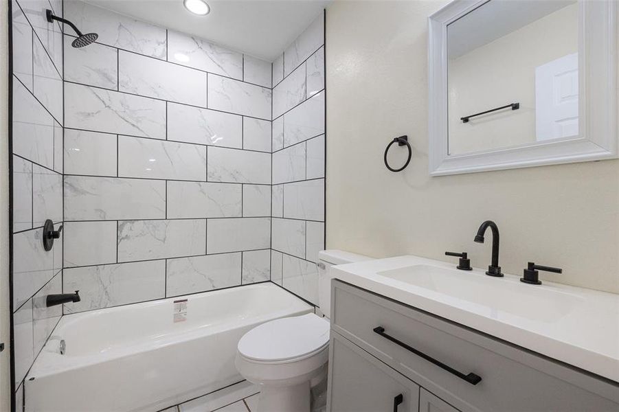 Full bathroom featuring vanity, tiled shower / bath, tile patterned flooring, and toilet