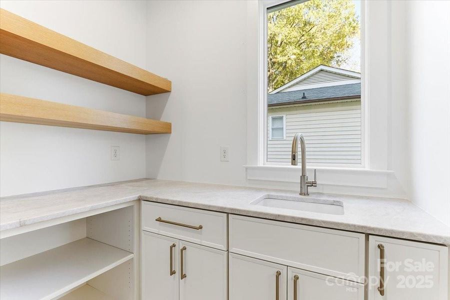 Laundry room with quartzite stone countertops, a full sink, storage areas, and room for double washer and dryer hookups. Laundry room with quartzite stone countertops, a full sink, storage areas, and room for double washer and dryer hookups.