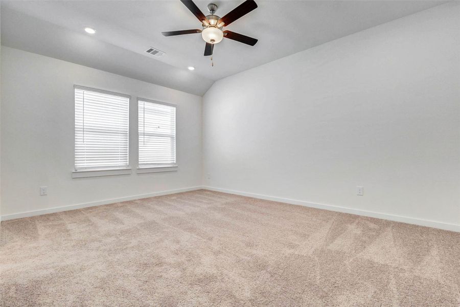 Secondary bedroom with soft carpet, white walls, recessed lighting, and a closet with double doors. The nearby hallway provides easy access to the main living areas and bathroom, creating a practical layout for everyday use.