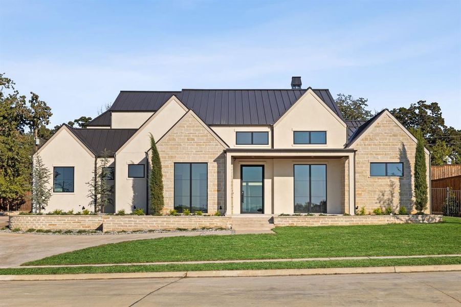 Modern farmhouse with stone siding, a porch, a standing seam roof, and a metal roof Modern farmhouse with stone siding, a porch, a standing seam roof, and a metal roof