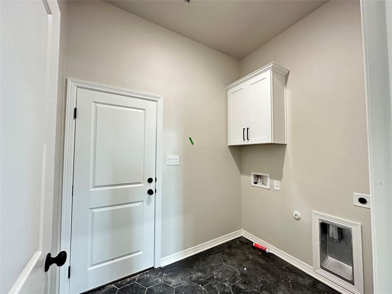 Laundry area featuring hookup for a gas dryer, washer hookup, cabinet space, and dark stone finish floors