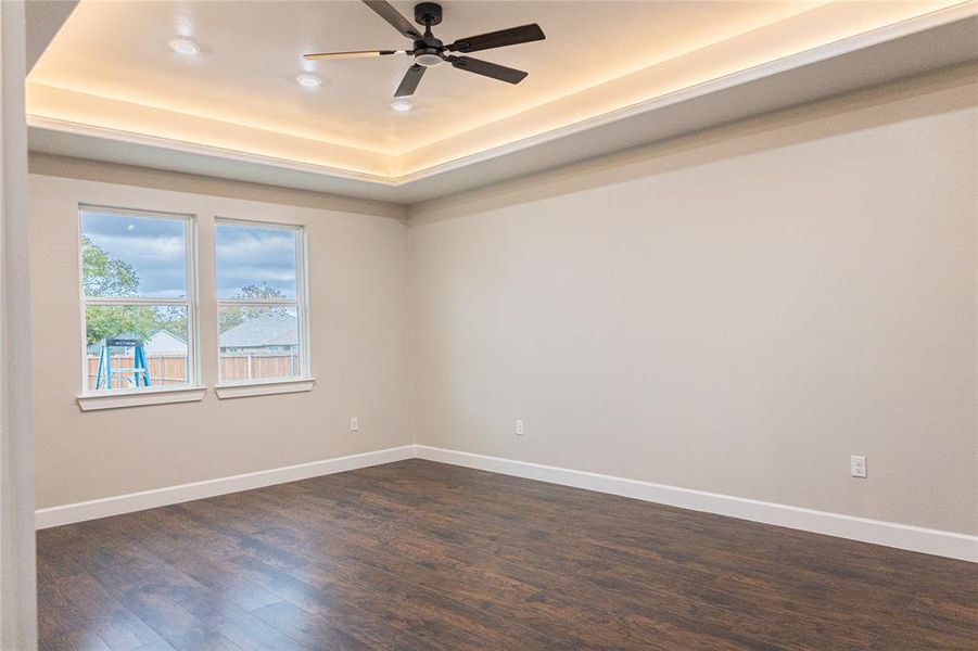Empty room with dark wood-style floors, a raised ceiling, a ceiling fan, and recessed lighting Empty room with dark wood-style floors, a raised ceiling, a ceiling fan, and recessed lighting