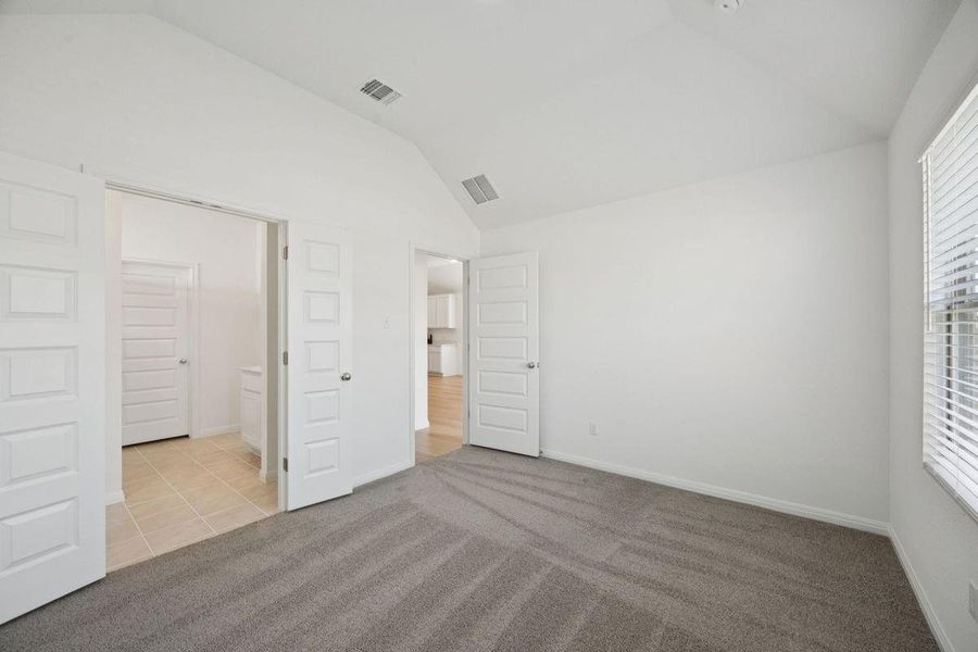 Unfurnished bedroom featuring lofted ceiling, carpet floors, and tile patterned floors