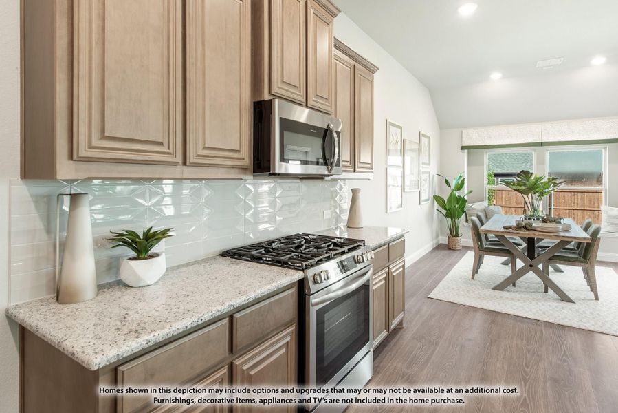 Kitchen with tan wood cabinets, granite countertops, stainless steel appliances, and open dining area with hardwood floors Kitchen with tan wood cabinets, granite countertops, stainless steel appliances, and open dining area with hardwood floors