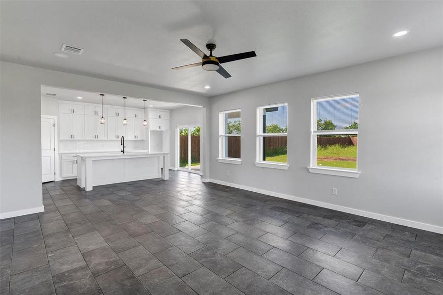 Unfurnished living room featuring a sink, plenty of natural light, baseboards, and recessed lighting