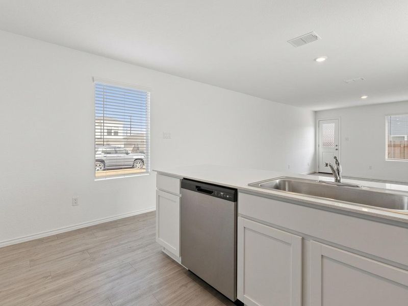 Photo has been enhanced with virtual modifications.  Kitchen with dishwasher, white cabinetry, light wood finished floors, and recessed lighting
