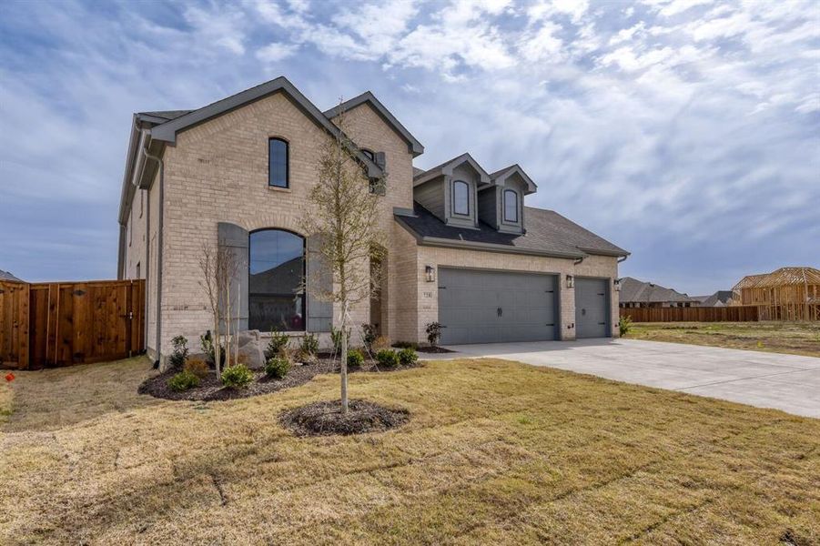 French country home featuring brick siding, driveway, and an attached garage