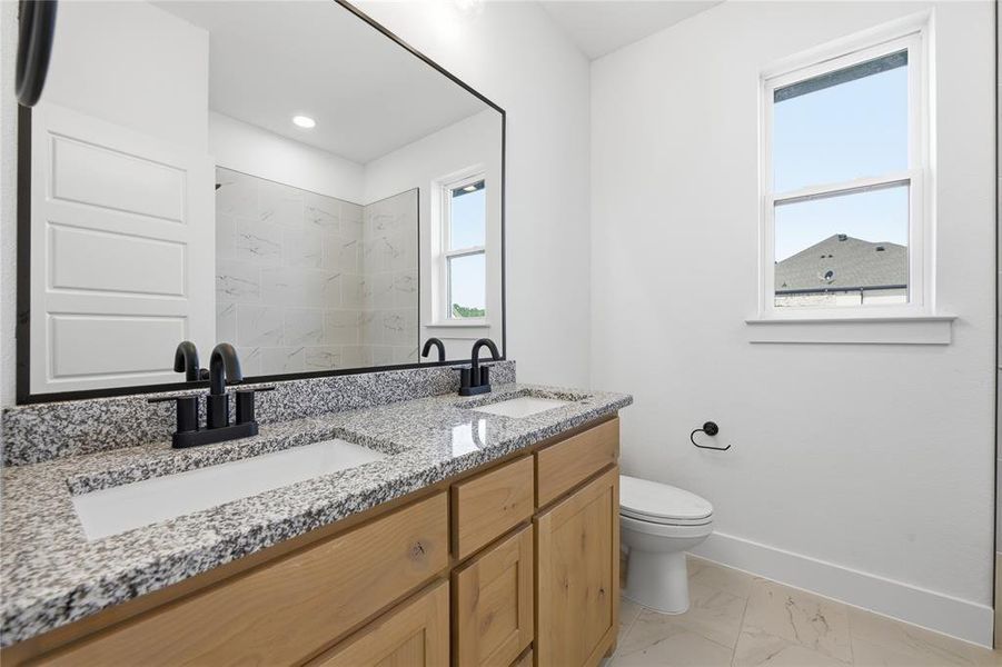Bathroom featuring double vanity, light marble finish floors, and a marble finish shower Bathroom featuring double vanity, light marble finish floors, and a marble finish shower