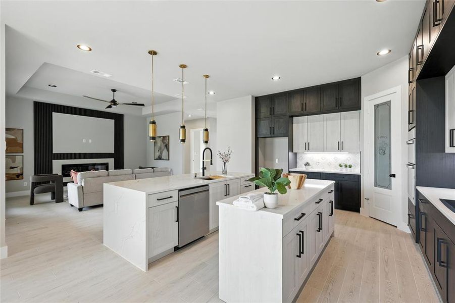 Kitchen featuring stainless steel appliances, an island with sink, ceiling fan, light wood-style floors, and tasteful backsplash
