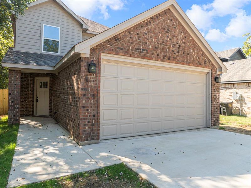 Traditional-style house featuring brick siding, a shingled roof, driveway, and an attached garage