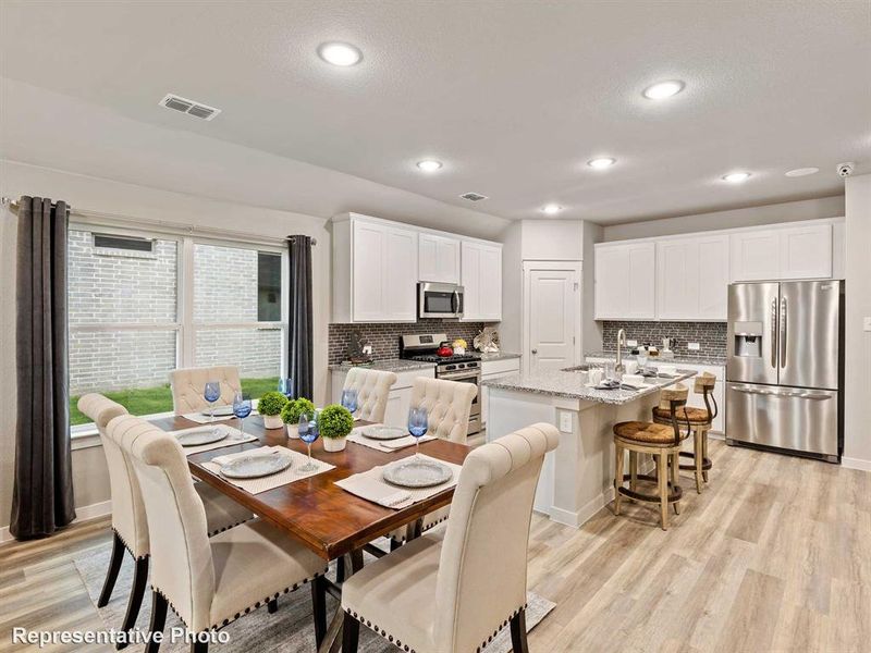 Open-concept living space featuring wood-finish flooring, recessed lighting, and a dining area with a view to the exterior
