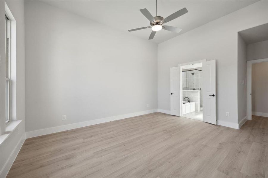 Unfurnished bedroom featuring ensuite bath, ceiling fan, and light hardwood / wood-style flooring