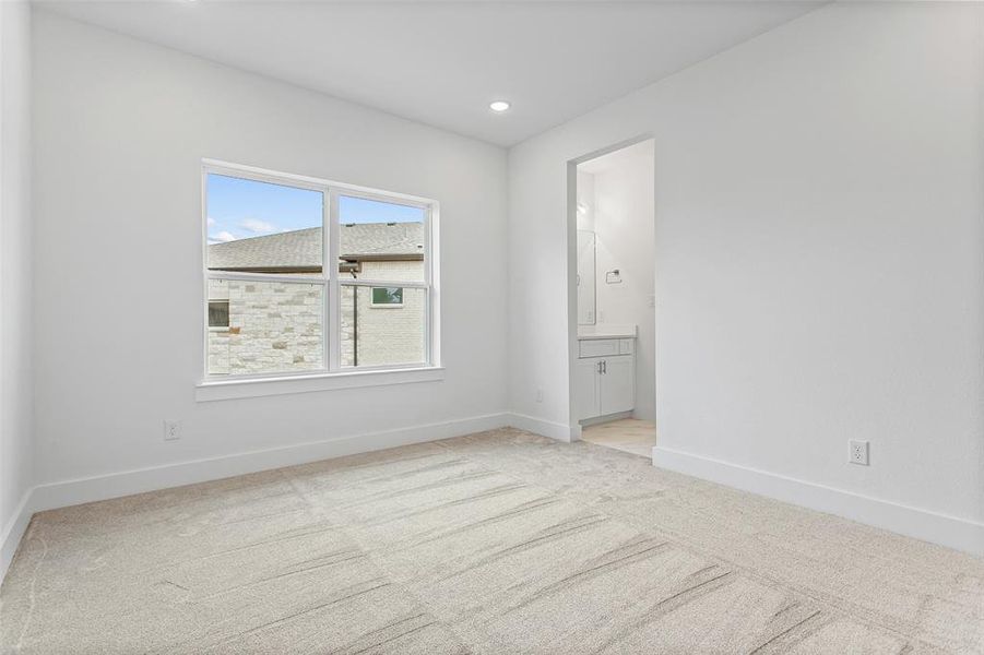 Unfurnished bedroom with ensuite bath and light carpet