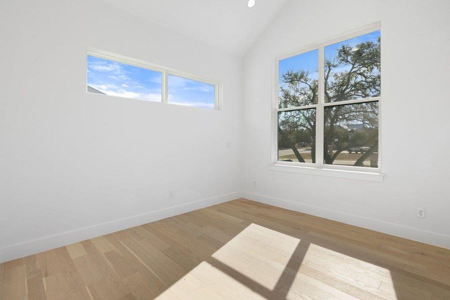 Empty room featuring light wood-style floors, vaulted ceiling, and recessed lighting