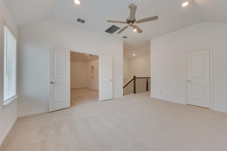 Unfurnished bedroom featuring vaulted ceiling, light colored carpet, and ceiling fan