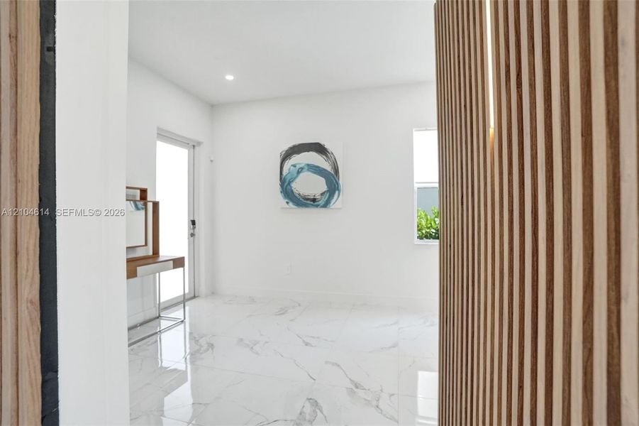 Wood slat wall paneling with integrated lighting, white walls, large format tile flooring, and a sliding glass door