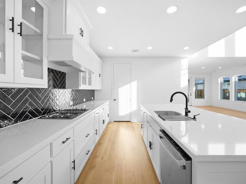 Kitchen with glass insert cabinets, white cabinetry, light wood-style floors, stainless steel appliances, and recessed lighting Kitchen with glass insert cabinets, white cabinetry, light wood-style floors, stainless steel appliances, and recessed lighting