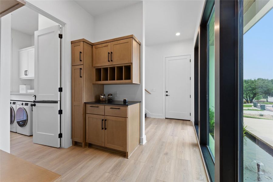 Entryway with wood-finish flooring, built-in cabinetry, and a dark countertop Entryway with wood-finish flooring, built-in cabinetry, and a dark countertop