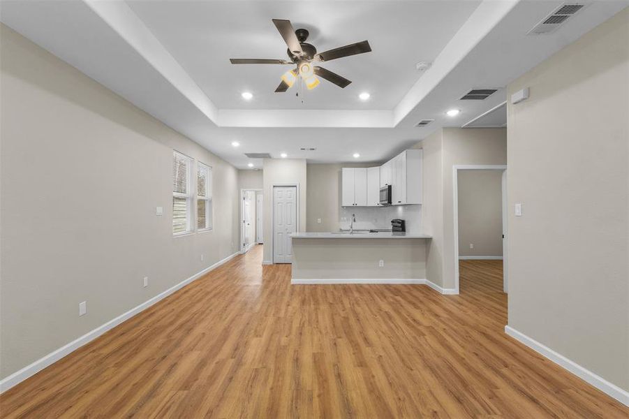 Kitchen featuring white cabinets, open floor plan, a peninsula, light countertops, and a ceiling fan