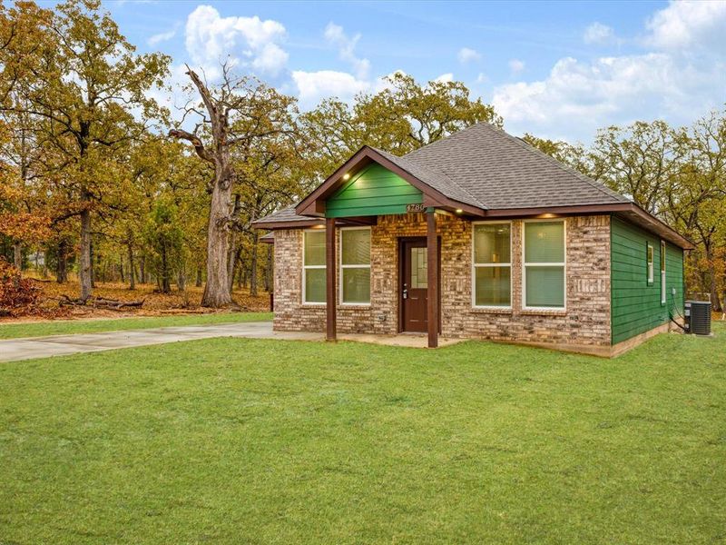 View of front of home featuring a front lawn, a shingled roof, and brick siding