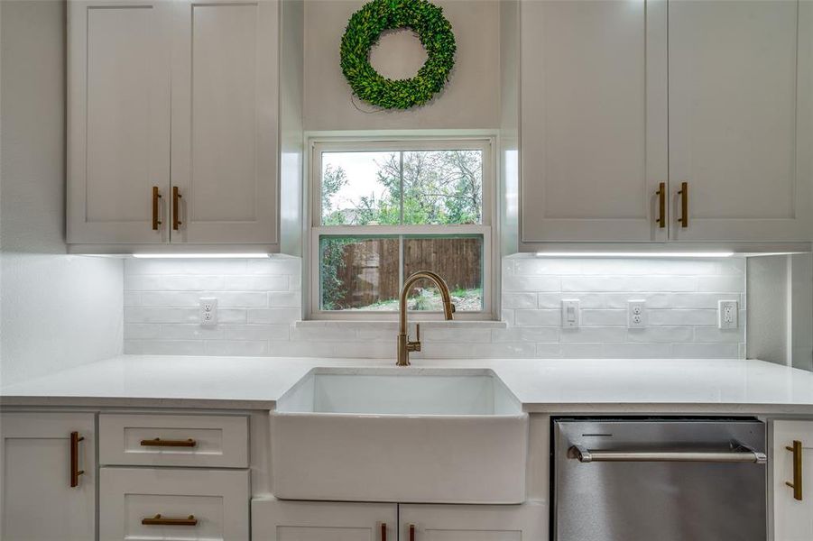 Kitchen featuring stainless steel dishwasher, sink, and tasteful backsplash