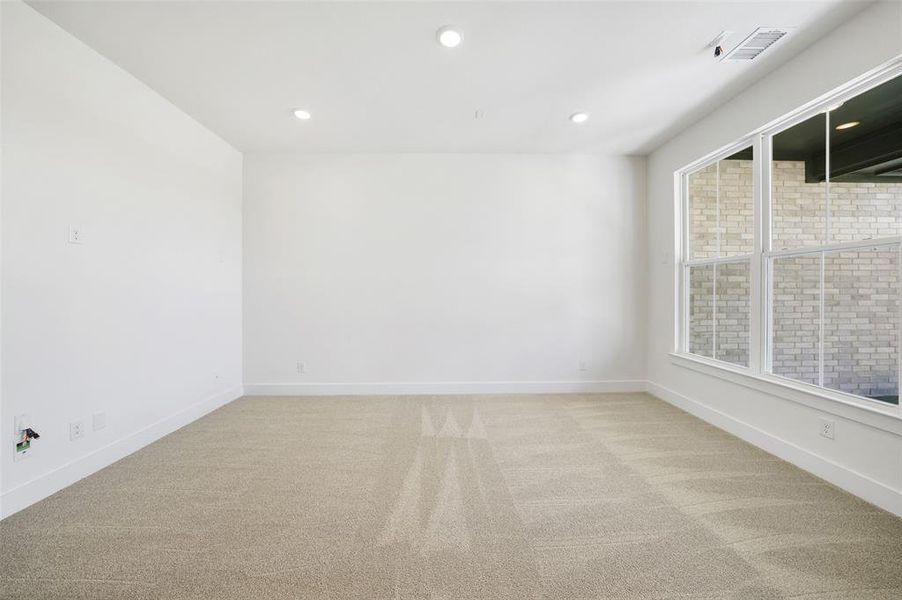 Empty room with light carpet and recessed lighting