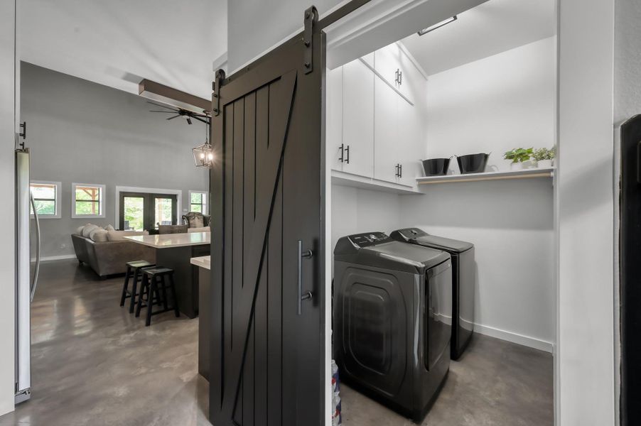 A stylish sliding barn door opens to the laundry room with storage above.