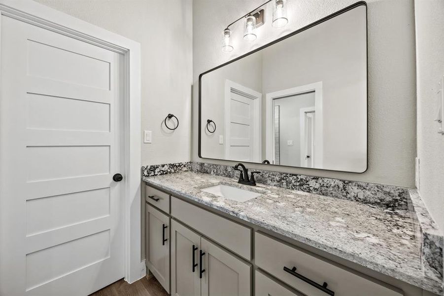 Bathroom with vanity, dark wood-style floors, and a textured wall Bathroom with vanity, dark wood-style floors, and a textured wall
