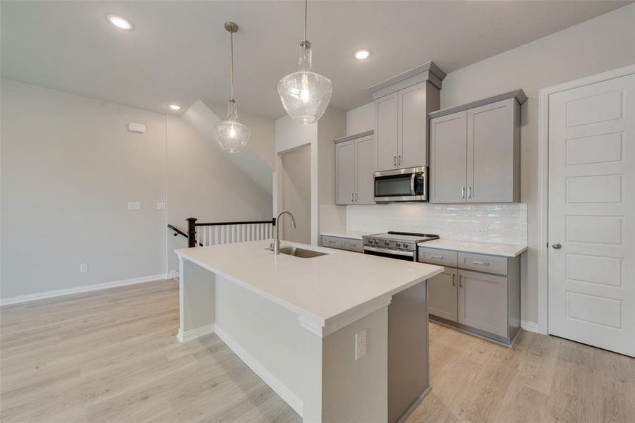 Kitchen featuring sink, appliances with stainless steel finishes, light hardwood / wood-style flooring, and decorative backsplash