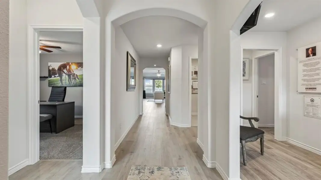 Inviting hallway with light wood-style flooring, archways, and recessed lighting
