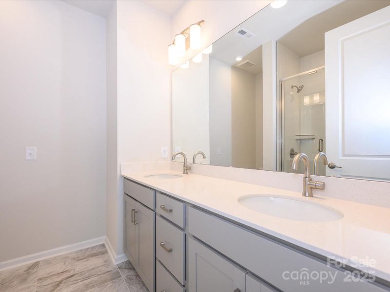 Dual vanity and modern tiles at en suite primary bath.