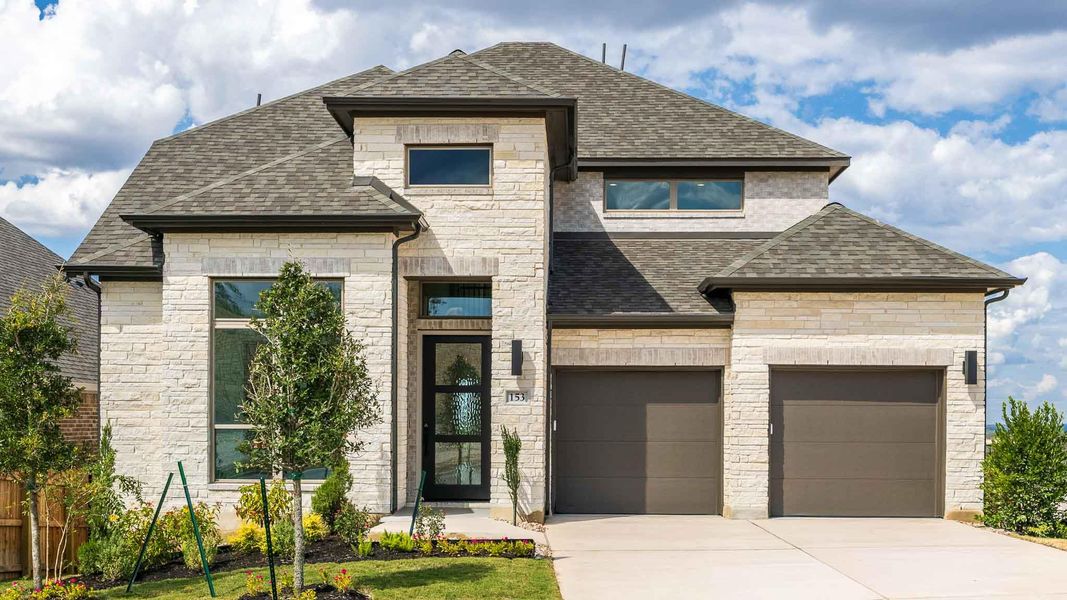 French country home with stone siding, a shingled roof, and concrete driveway French country home with stone siding, a shingled roof, and concrete driveway