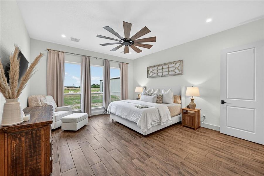 Spacious room featuring wood-finish flooring, a contemporary ceiling fan, recessed lighting, and a white panel door