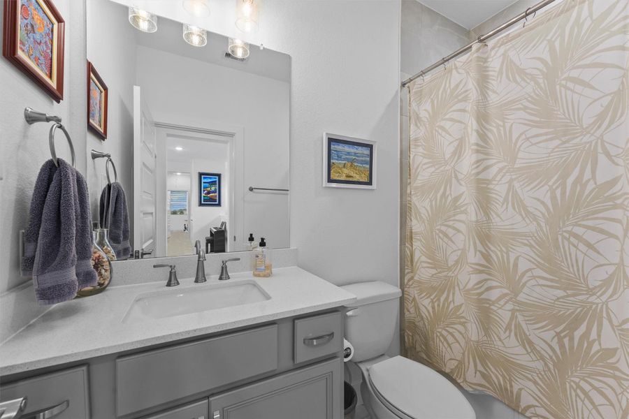 This secondary bathroom is well-appointed with a single vanity and stylish quartz countertops. It features a tub/shower combination, offering convenience and comfort for family and guests.