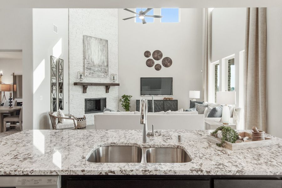 Kitchen island with granite countertop and double sink overlooking open living room with fireplace and high ceilings Kitchen island with granite countertop and double sink overlooking open living room with fireplace and high ceilings