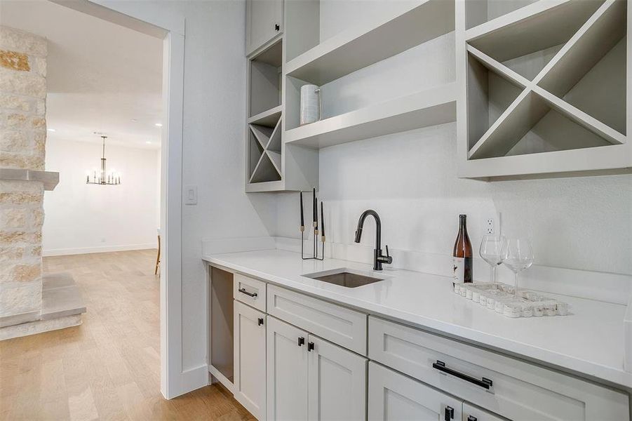 Kitchen featuring hanging light fixtures, sink, a chandelier, white cabinetry, and light hardwood / wood-style floors