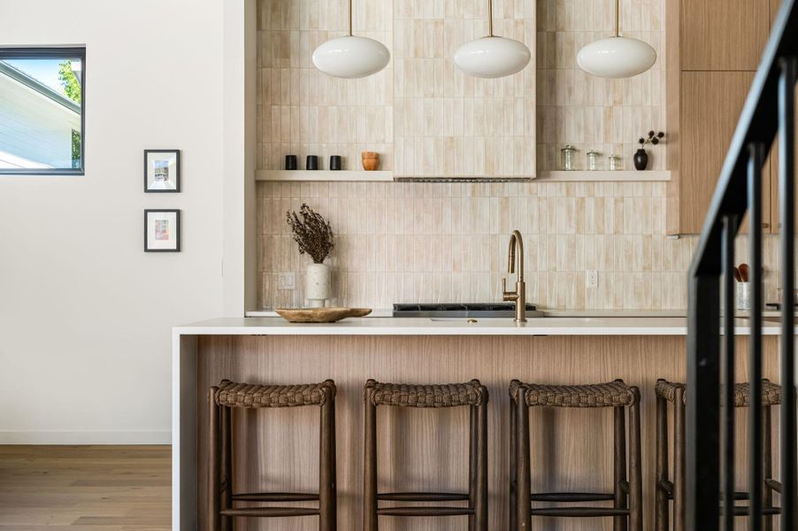 Clean architectural lines define this modern kitchen area highlighting a stone-topped island and warm wood finishes.