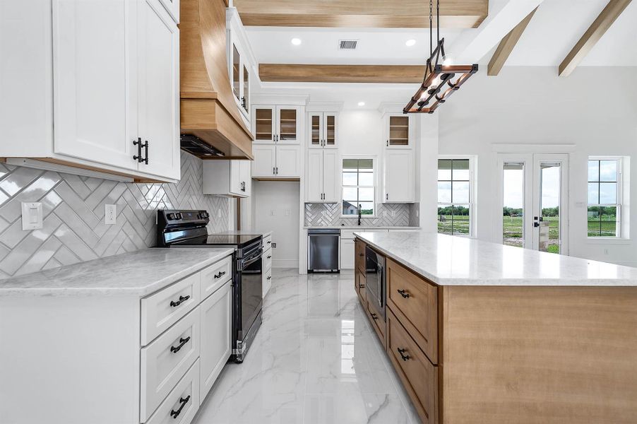 Another view of the kitchen showcasing the spacious island, custom cabinetry, wood accents, and natural light throughout. Another view of the kitchen showcasing the spacious island, custom cabinetry, wood accents, and natural light throughout.