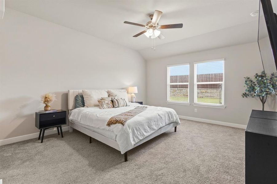 Spacious bedroom featuring light neutral wall paint, vaulted ceilings, and plush gray carpeting Spacious bedroom featuring light neutral wall paint, vaulted ceilings, and plush gray carpeting