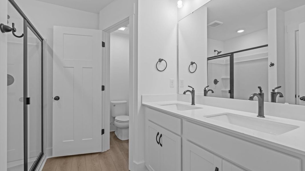 Accomplished design shines in this primary bath with dual vanity and a sleek walk-in shower Accomplished design shines in this primary bath with dual vanity and a sleek walk-in shower