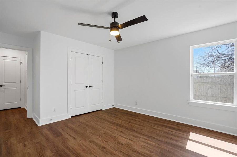 Unfurnished bedroom featuring a closet, a ceiling fan, baseboards, and dark wood-style flooring