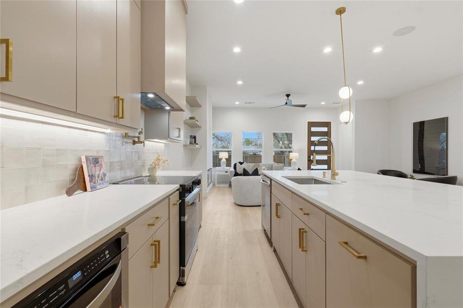 Kitchen featuring open floor plan, light stone countertops, hanging light fixtures, stainless steel appliances, and light wood finished floors Kitchen featuring open floor plan, light stone countertops, hanging light fixtures, stainless steel appliances, and light wood finished floors