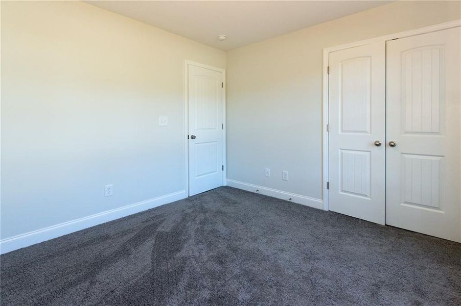 Unfurnished bedroom with dark colored carpet and a closet